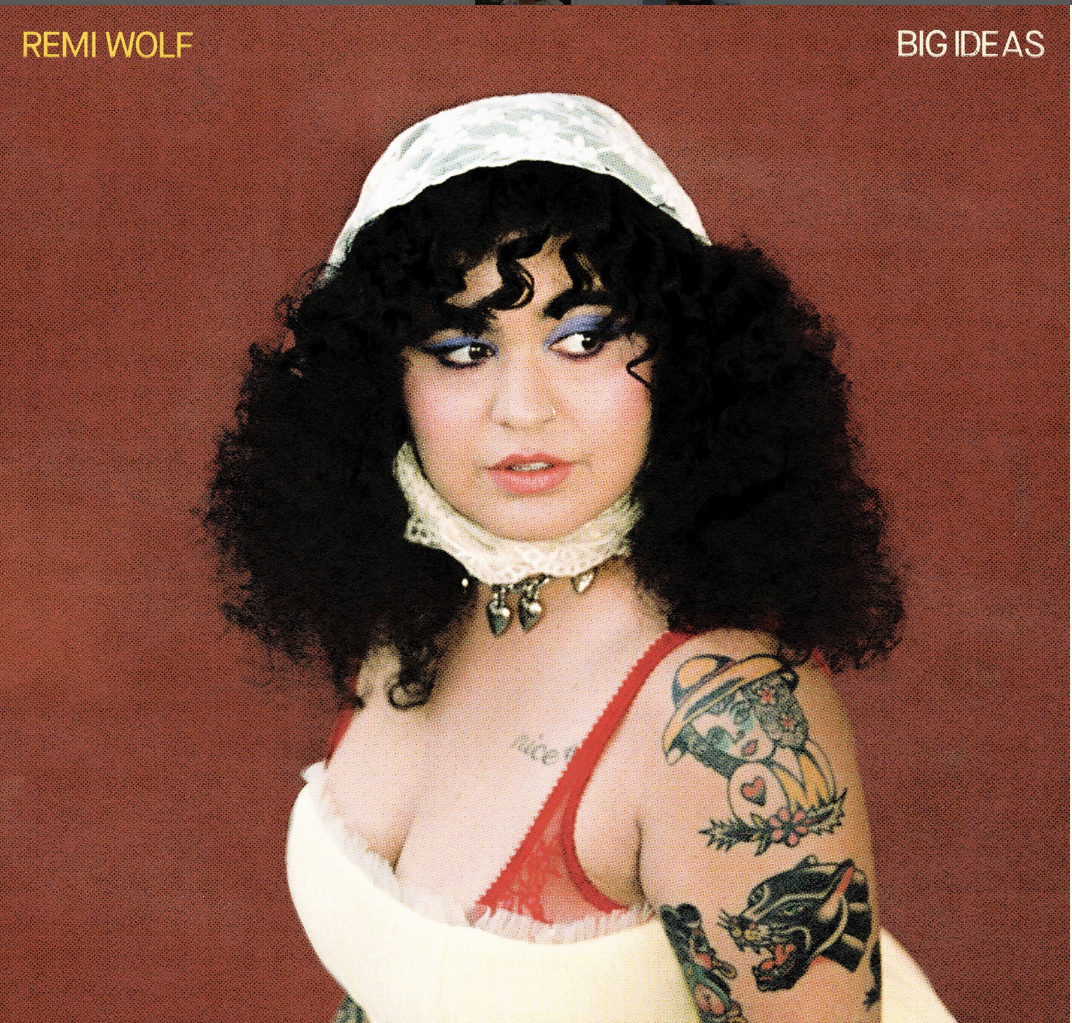 A woman poses looking to the right side against a burgundy red background while wearing a white outfit.